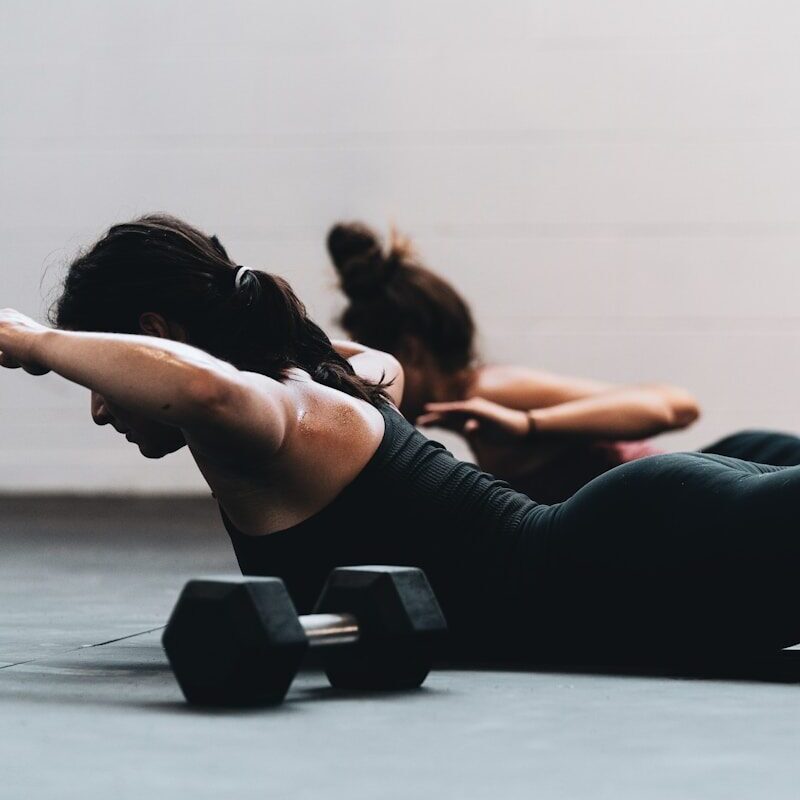 woman in black tank top and black leggings lying on black floor
